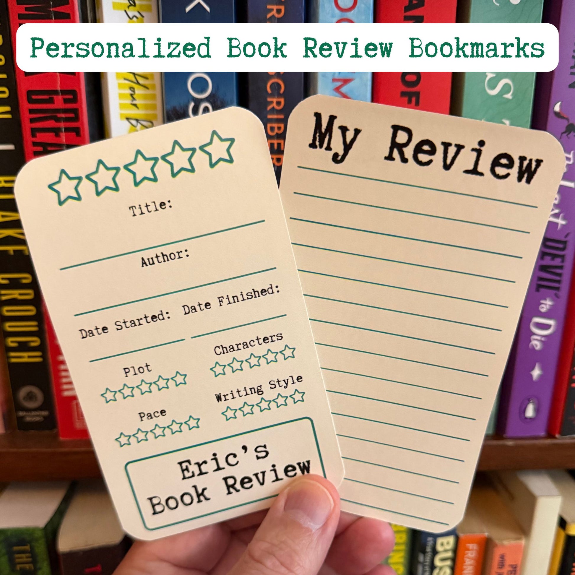 A hand holds two personalized book review bookmarks in front of a bookshelf. One bookmark has a cream background with green lines and star rating icons, and the other has lined writing space with the heading 'My Review'.